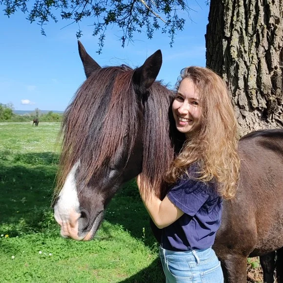 Romane Bédu, naturopathe équin, aux côtés de son cheval dans un pré près de Dijon